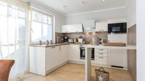 A modern kitchen with white cabinets, a built-in oven, a microwave, and a coffee maker.