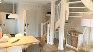 Eine moderne Küche mit Essbereich, einer Treppe und einer kleinen Sitzecke.