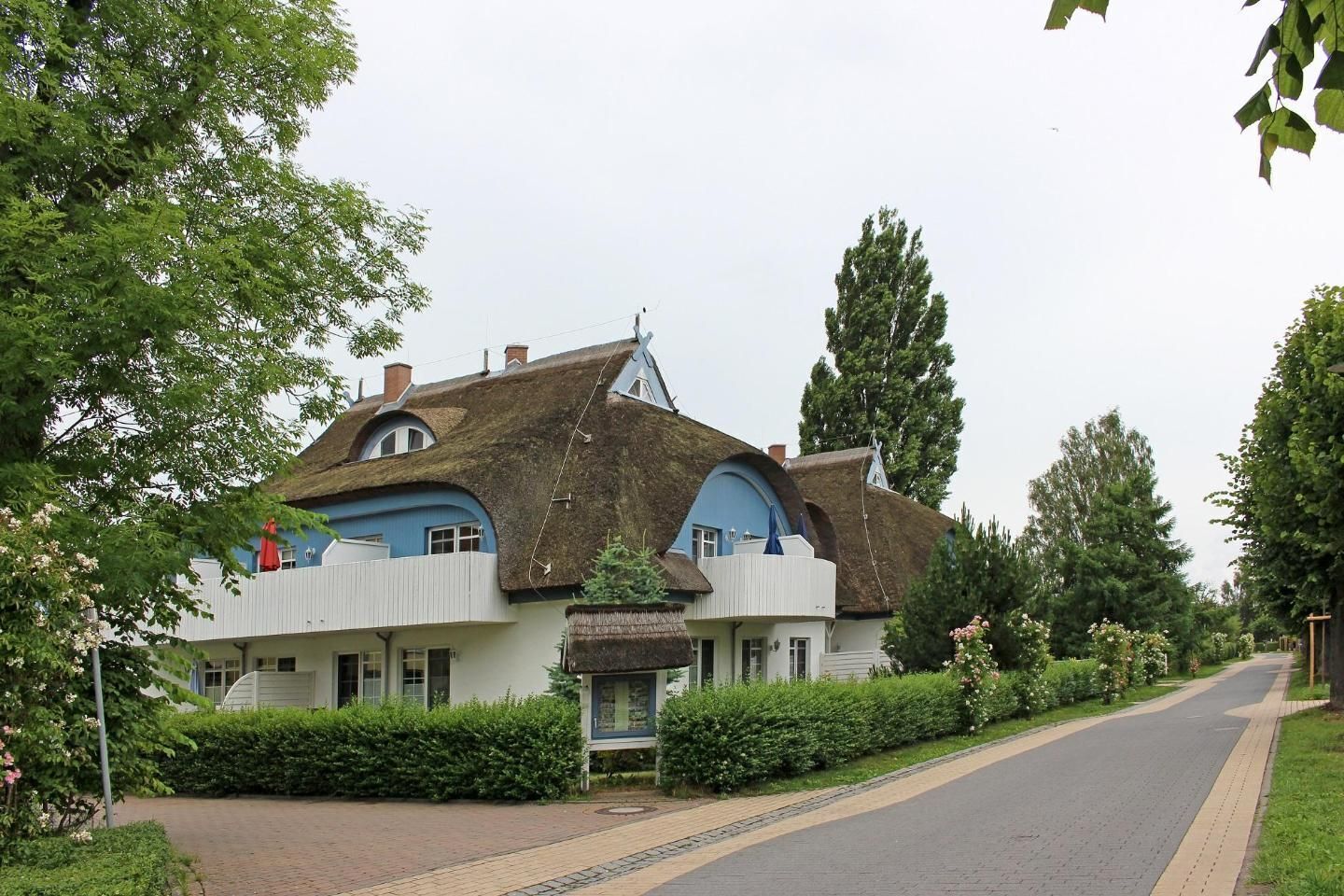 A house with a unique thatched roof and a blue and white exterior.
