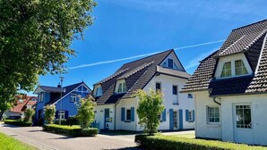 Een rij traditionele Europese huizen met schuine daken, een geplaveid pad en verzorgde hagen.