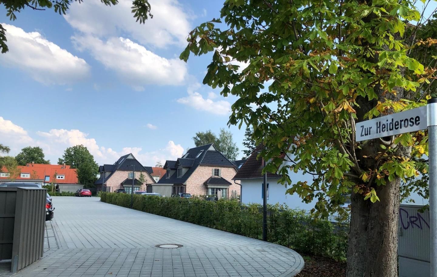 Un quartier résidentiel avec des maisons, une allée pavée et un panneau de signalisation indiquant « Zur Heiderose ».