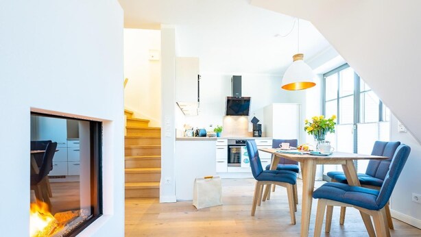 Una cucina moderna con zona pranzo, camino e scalinata che conduce a un altro piano.