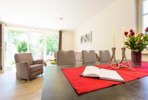Une pièce spacieuse avec une grande fenêtre, une table à manger agrémentée d’un chemin de table rouge et plusieurs chaises rembourrées.