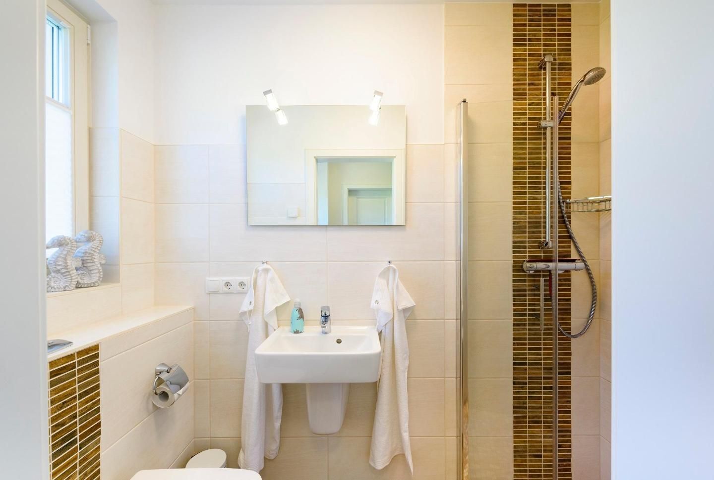 A modern bathroom with a white sink, a mirror, and a shower.