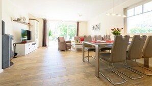 Una sala de estar moderna con televisor, sofá, mesa de comedor y sillas.