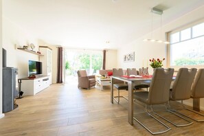 Un salon moderne comprenant un téléviseur, un canapé, une table à manger et des chaises.