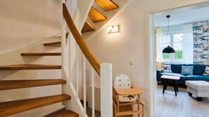 Eine Treppe mit Holzstufen und weißen Geländern, die zu einem Raum mit einem blauen Sofa und einem kleinen Tisch führt.