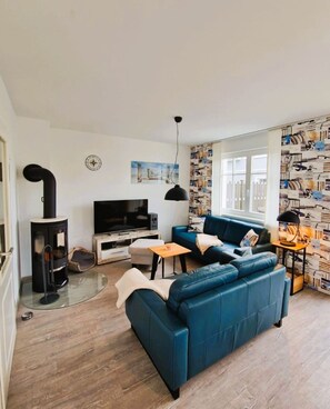 A living room with a blue sofa, a TV, a fireplace, and a patterned wall.