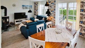 Ein stilvolles Wohnzimmer mit einer Couch, Fernseher und einem Essbereich mit Tisch und Stühlen.