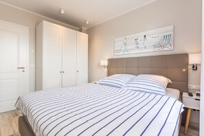 Un dormitorio con una cama grande, cabecera, mesita de noche, lámpara de pared y un cuadro.