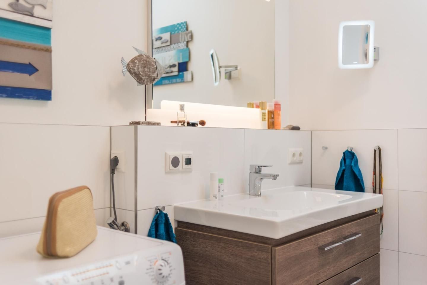 Une salle de bain avec un lavabo blanc, un miroir et un meuble en bois.