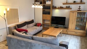 Un salon comprenant un canapé, une table basse, un téléviseur et un meuble contenant de la verrerie.