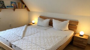 Un lit double avec une tête de lit en bois, deux tables de chevet avec des lampes et une bibliothèque au-dessus du lit.