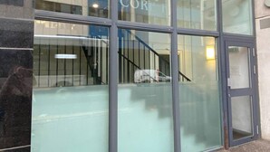 Eine moderne Gebäudefassade mit großen Fenstern und einer sichtbaren Treppe.