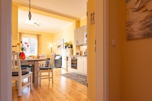A cozy kitchen with wooden cabinets, a dining area with a table and chairs, and a hanging light fixture.