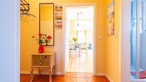 A hallway with a wooden cabinet, a red vase with flowers, and a mirror on the wall. - Neue Reihe 22 Whg. 1 "Villa Balticum" - Modern vacation apartment close to the center (Zingst)
