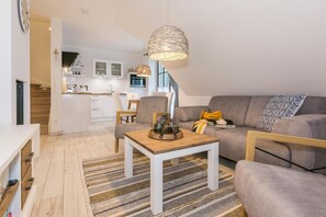 Una sala de estar moderna con un sofá, una mesa de centro y un comedor con cocina al fondo.