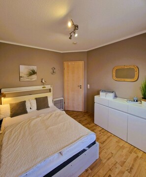 Un dormitorio con cama, cómoda, espejo y lámpara en el techo.