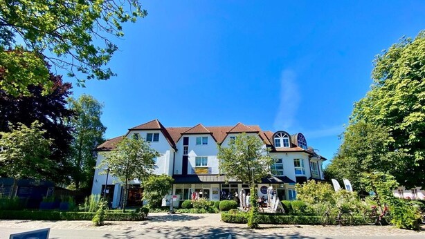 A two-story building with a red-tiled roof, surrounded by greenery and a paved area with a 'Final Sale' sign. - Strandstrasse 51 Whg. 2 - simple vacation apartment including Netflix (Zingst)