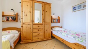 A bedroom with two beds, wooden wardrobe, and shelves with books. - Strandstrasse 51 Whg. 2 - simple vacation apartment including Netflix (Zingst)