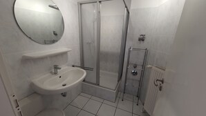 Et badeværelse med vask, toilet, bruser og et spejl.