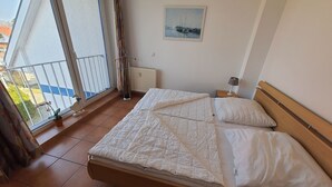 Et soveværelse med seng, et vindue der viser udsigt til både, en radiator og et billede på væggen.