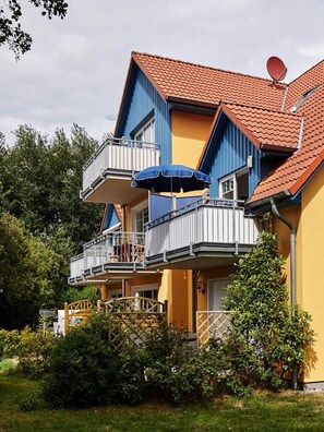 Monikerroksinen rakennus, jossa on parvekkeita, satelliittiantenni ja puutarha-alue.