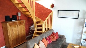 Una sala de estar con sofá gris, escalera de madera y un mueble de madera.
