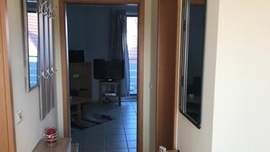 En gang med et træskab, et lille bord med klodser der staver "HOME", og et fjernsyn i baggrunden.