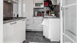 A modern kitchen with white cabinetry, a granite countertop, and a built-in microwave.