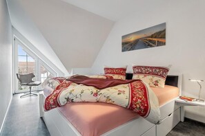 Ein Schlafzimmer mit einem Bett, einem Sessel, einem Nachttisch und einem Bild an der Wand.