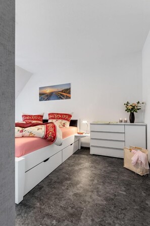 Une chambre à coucher avec un lit, une table de chevet, une commode et un tableau au mur.