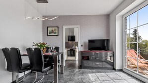 A modern living room with a dining area, a TV, and a large window with a view.