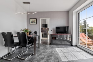 Un salon moderne comprenant un coin repas, un téléviseur et une grande fenêtre offrant une belle vue.