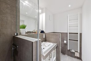 Un baño moderno con cabina de ducha de vidrio, un lavabo blanco y un perchero para toallas.