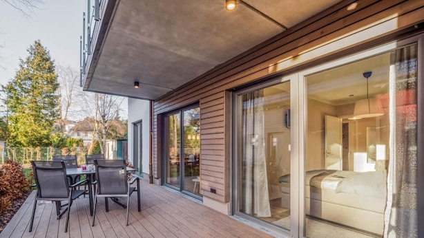 A modern hotel room with a large sliding glass door, a wooden deck, and a view of the surrounding area.