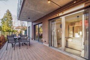 Ein modernes Hotelzimmer mit einer großen Schiebeglasdoor, einer Holzterrasse und Blick auf die Umgebung.