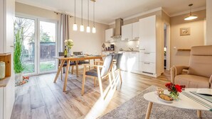 A modern kitchen with white cabinets, a dining area with a wooden table and chairs, and a cozy living space with a sofa and a coffee table.