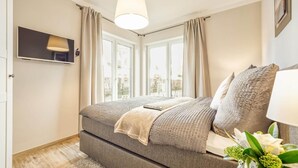 A bedroom with a bed, a hanging light, a window, and a view of the outdoors.