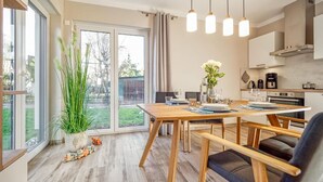 A modern kitchen with a dining area, large windows, and a view of the backyard.