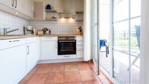 Een moderne keuken met witte kastjes, een ingebouwde oven en een groot raam met uitzicht op de omgeving.