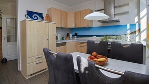 Une cuisine moderne avec des meubles en bois, une table à manger avec des chaises et une vue sur la plage par une fenêtre.