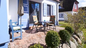 Une terrasse avec une table et des chaises, une chaise bleue et une porte avec un rideau.