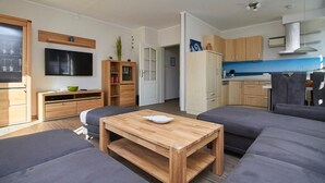 Un salon moderne avec une table basse en bois, des canapés gris et un téléviseur à écran plat.