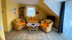 Un salón acogedor con dos sillones de mimbre, un sofá central y una pequeña mesa de centro.