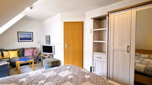 Una camera da letto con un letto grande, una televisione, una porta in legno e un armadio.