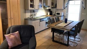 Cucina compatta con zona pranzo, caratterizzata da un armadietto in legno, un forno a microonde e un tavolo con sedie.
