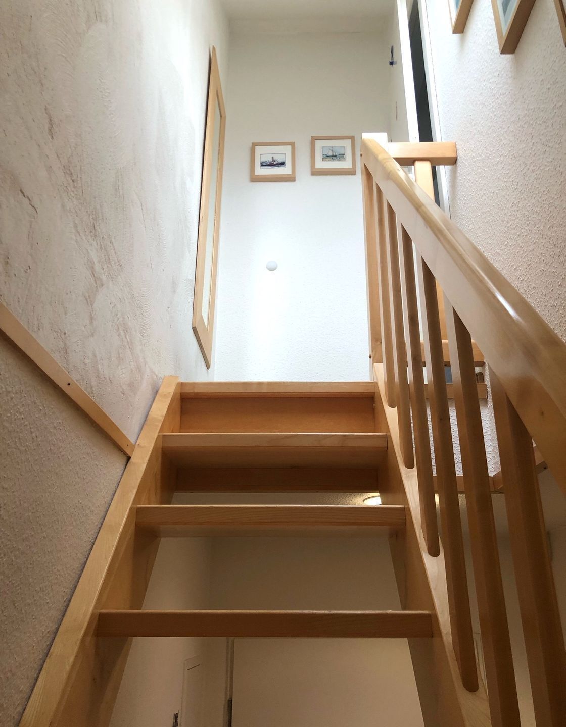 Un escalier en bois, doté d’une rampe, mène à un palier.