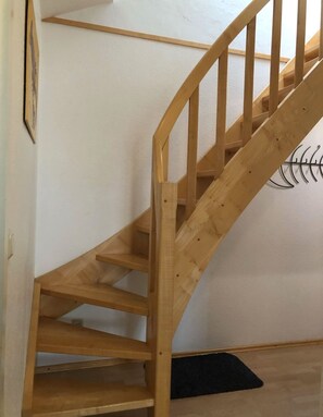 A wooden staircase with a handrail, leading to a landing with a black mat. - Strandstrasse 51 Whg. 11 - Modern and comfortable vacation apartment (Zingst)