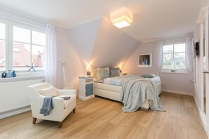 Une chambre à coucher avec un lit, une chaise, une table de chevet et une fenêtre.